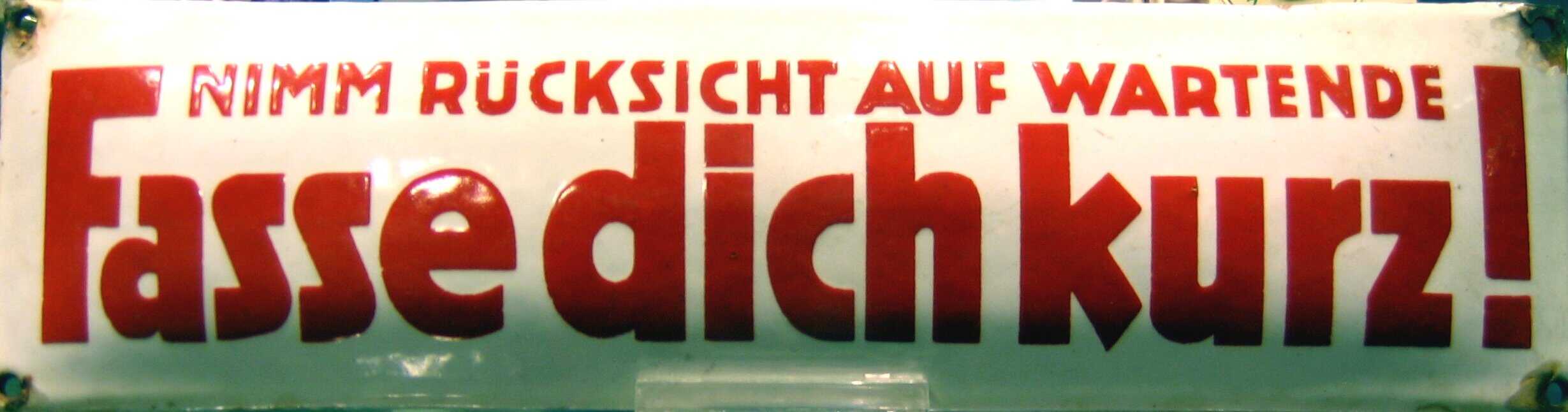 An old sign asking users of public pay phones to keep their conversations brief